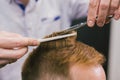 Barber Making Haircut Bearded Man In Barbershop. Professional stylist cutting client hair in salon. Barber using Royalty Free Stock Photo