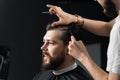 Barber making hairstyle for confident bearded hipster. Advertising for barbershop and men& x27;s beauty salon.