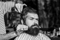 Barber man serving client at barber shop. Vintage barbershop, shaving. Brutal bearded guy viziting hairstylist in barber shop. Royalty Free Stock Photo