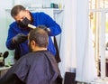 Barber in medical mask cutting hair in barber shop, barber cutting hair Royalty Free Stock Photo