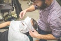 Barber softening male face skin with hot towel at barbershop
