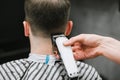 Barber`s hand with a clipper cuts the back of a man`s neck. Haircuts in barbershop. Hairdresser shaves a young man hair clipper.