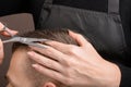The Barber`s hand with a pair of scissors for cutting the hair of a young man. Creating a stylish men`s haircut in a barbershop. Royalty Free Stock Photo