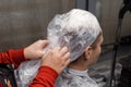 Barber's hands, close-up, remove a protective film from the client's head, the process of dyeing hair in a hairdresser