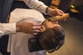 Professional barber carefully trimming the clients beard