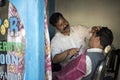 A barber shave the beard of a customer lying on antique barber chair inside hair saloon.