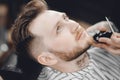 Barber shaves client beard in men barbershop with razor