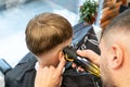 Barber shaves male client hair with sharp trimmer in barbershop closeup. Skilled hairstylist cuts man hair on occiput Royalty Free Stock Photo