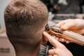 Barber shaves male client hair with trimmer in barbershop Royalty Free Stock Photo