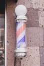 Barber sign and male hairdresser pole or staff mounted on wall. Helix of colored stripes red white and blue Royalty Free Stock Photo