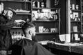 Barber styling hair of bearded client with wax. Hipster client getting hairstyle. Barbershop concept. Man with beard and