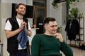 Barber talking to caucasian client man while sitting in chair