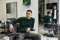 Barber talking to caucasian client man while sitting in chair