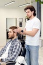 Barber talking to caucasian man while sitting in chair