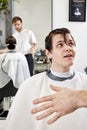 Barber talking to caucasian man while sitting in chair