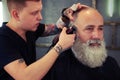 Barber with tattoo making haircut to handsome hipster senior man Royalty Free Stock Photo