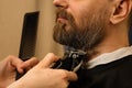 Barber trimming beard with electric razor