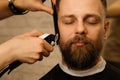 Barber trimming beard with electric razor