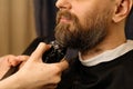 Barber trimming beard with electric razor