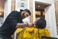 A barber trimming his client beard with an electric shaver