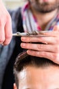 Barber trimming man hair in haircutter shop