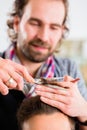 Barber trimming man hair in haircutter shop