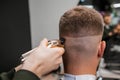 Barber trims the back of a mans head with a trimmer at the barbershop. Royalty Free Stock Photo