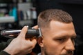 Barber uses trimmer to cut client hair in barbershop Royalty Free Stock Photo