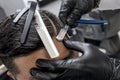 A barber wearing gloves uses a shaving knife to create a hard part. Classic and trendy haircut style. At a barbershop