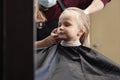 Barber woman make fashionable pretty hairstyle for cute little girl