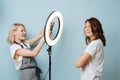 Barber woman is taking photo of a client with the help of ring lamp