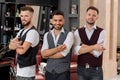 Barbers wearing white shirts showing posing with crossed hands. Royalty Free Stock Photo