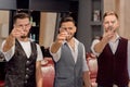 Barbers wearing white shirts and vests looking through scissors at camera. Royalty Free Stock Photo