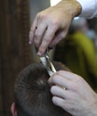 At a barbershop. Barber hands cutting customer hair with scissors and comb Royalty Free Stock Photo