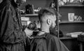 Barbershop concept. Hipster bearded client got hairstyle. Barber with hairdryer blows off hair out of cape. Barber with Royalty Free Stock Photo