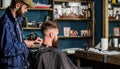 Barbershop concept. Hipster bearded client got hairstyle. Barber with hairdryer works on hairstyle for bearded man Royalty Free Stock Photo