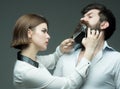 Barbershop or hairdresser concept. Woman hairdresser cuts beard with scissors. Guy with modern hairstyle visiting