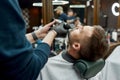 Barbershop salon. Barber in black gloves making moustache correction with electrical raser. Young man visiting