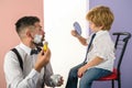 Barbershop. Trendy and stylish father and son. Barber shaving a bearded man in a barber shop. Barber Shop Studios