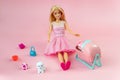 Barbie doll with loose blond hair in a pink dress standing on a blue background. barbie mother with a baby in bed Royalty Free Stock Photo