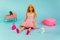 Barbie doll with loose blond hair sitting on a blue background