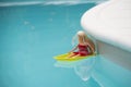Barbie doll sitting in a plastic boat flotting in the swimming pool