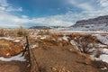 Barbwire fence in front of red rock field and large mesa plateau in rural New Mexico