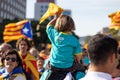 Little girl holding a flag with ANC pro-independence shirt over his father`s shoulders. Rally at La Diada, Catalonia`s National