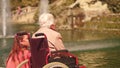 BARCELONA, SPAIN - APRIL, 16, 2017. Handicapped senior woman in a wheelchair and her daughter near park fountain