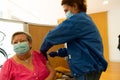 Barcelona, Spain - 4 april 2021: a nurse with syringe giving covid19 or coronavirus vaccine in clinic to a senior person.