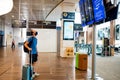 Barcelona, Spain - 20 august 2020: traveller with face mask at the airport with trolley, looking at flights schedule, alone in