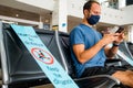 Barcelona, Spain - 20 august 2020: young man inside airport with face mask and social distancing sign, traveling in the time of Royalty Free Stock Photo