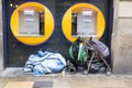BARCELONA, SPAIN, February 4, 2018 Homeless man covered with blankets sleeping under ATMs, near him stands a stroller with his st