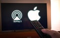 Barcelona, Spain. January 2019: Man holds a remote control With the Apple and Airplay2 icon screen on TV